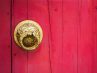 Antique Chinese brass doorknob on a red wooden door
