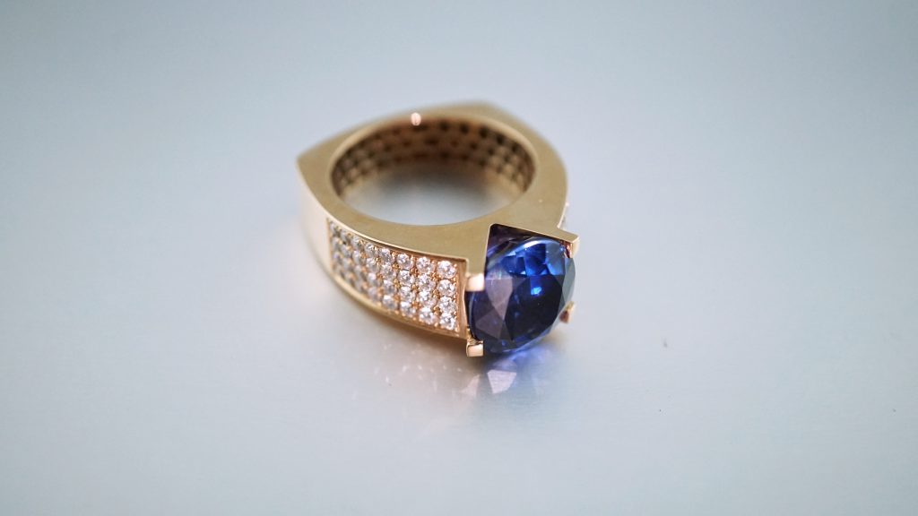 Gold ring with inlaid diamonds and a blue stone