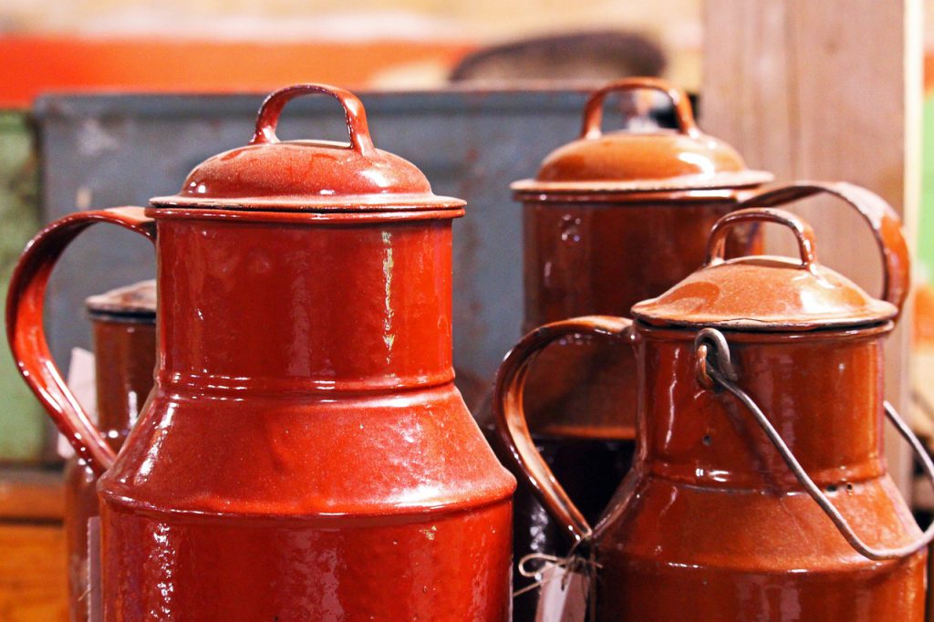Closeup image of three antique red milk cans