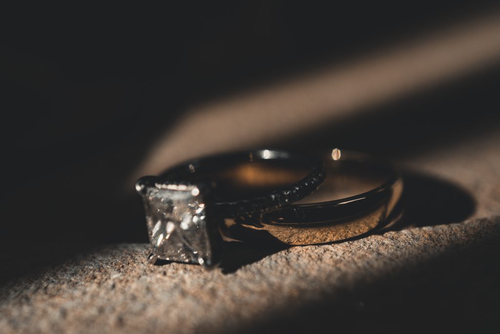 Gold ring with diamond stone set against a brown background