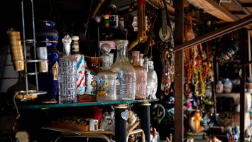 Antique glass bottles and other items on a cluttered shelf