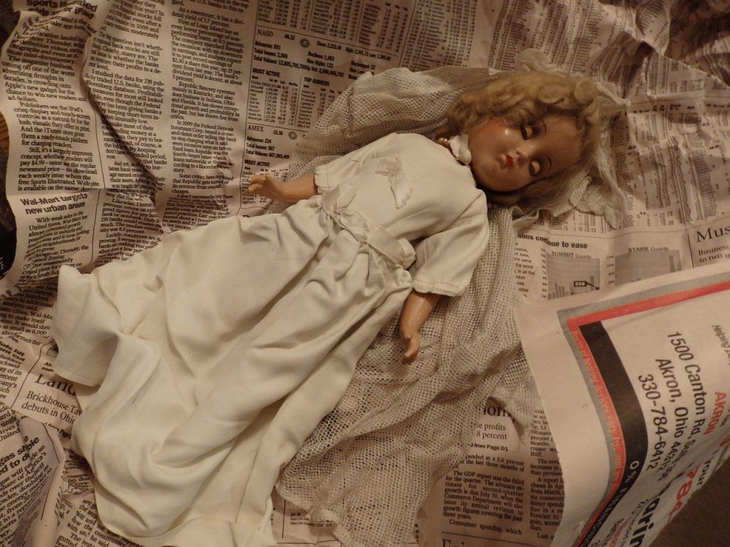 Porcelain doll lying on newspaper