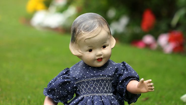 Plastic girl doll sitting on grass