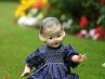 Plastic girl doll sitting on grass