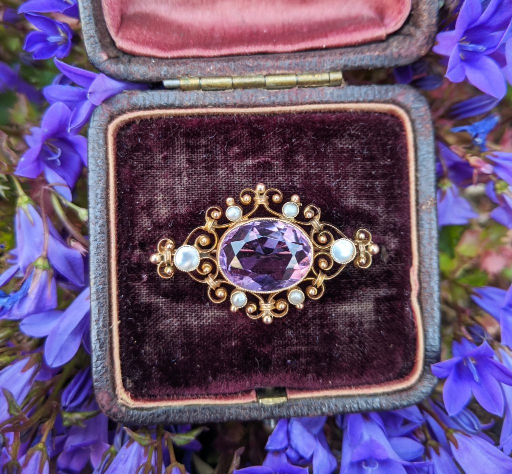 Purple sapphire and diamond bracelet in a purple velvet box on a bed of purple flower petals