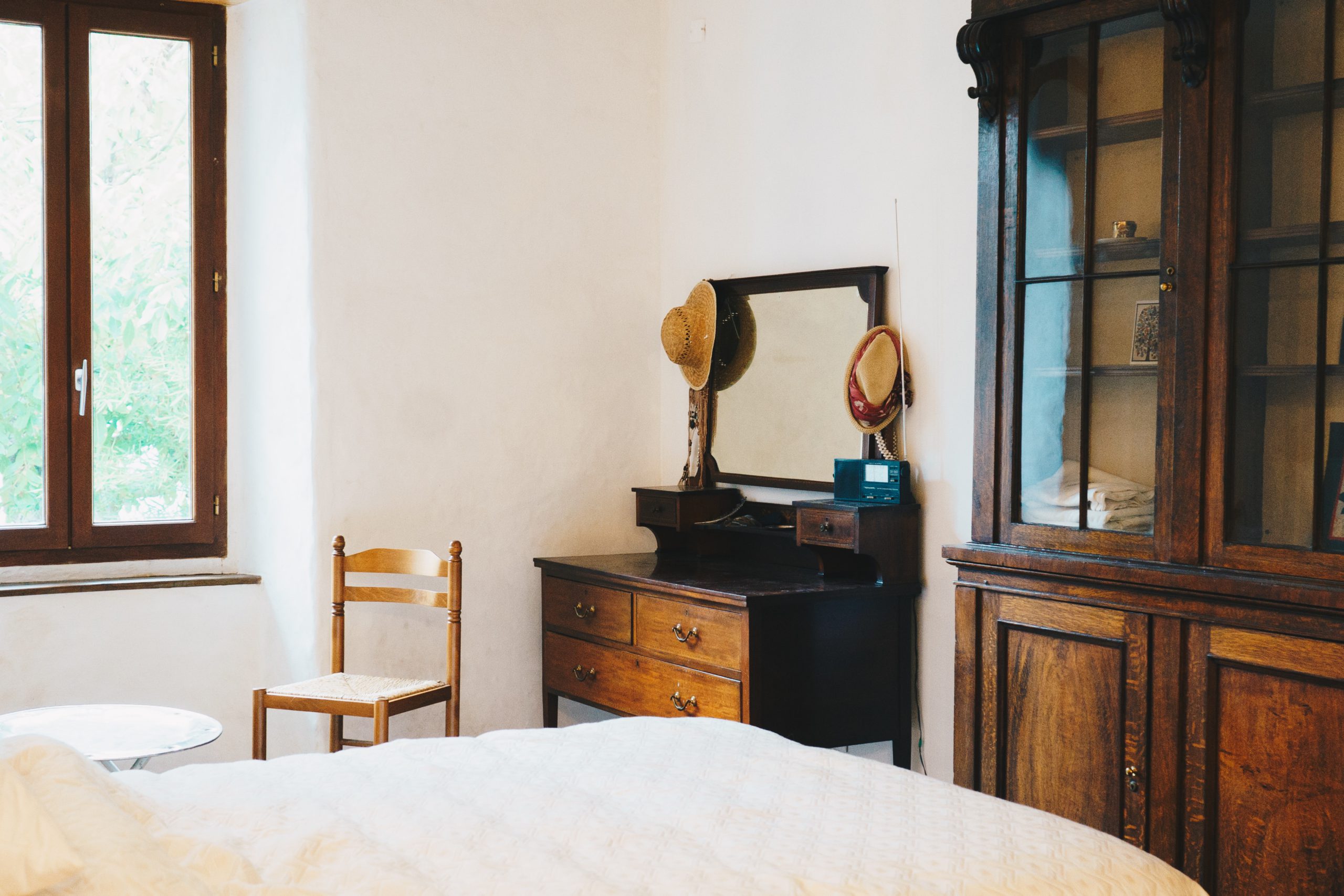 Bedroom with an antique dark wood washstand behind a white bed.