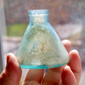 Small blue antique glass vase held in a hand.