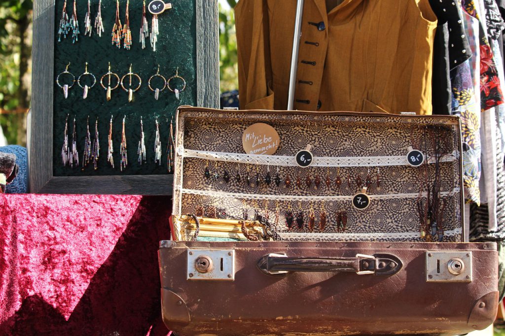 Antique jewelry displayed in a suitcase at a flea market