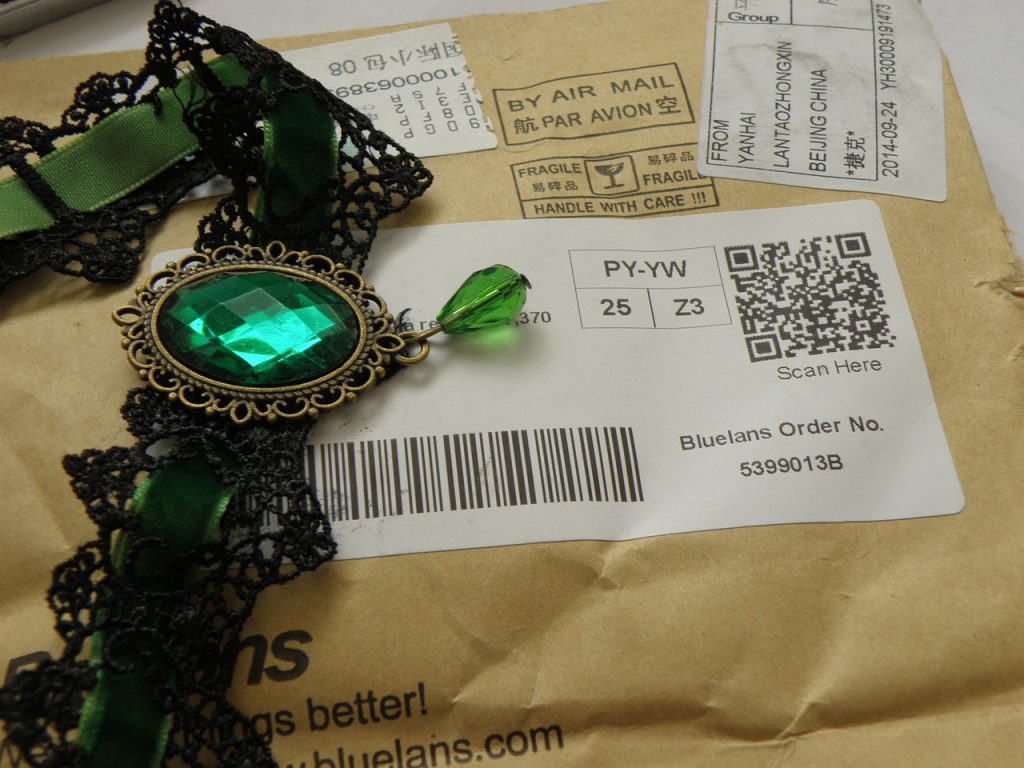 Lace necklace with green stone pendant on top of a shipping envelope