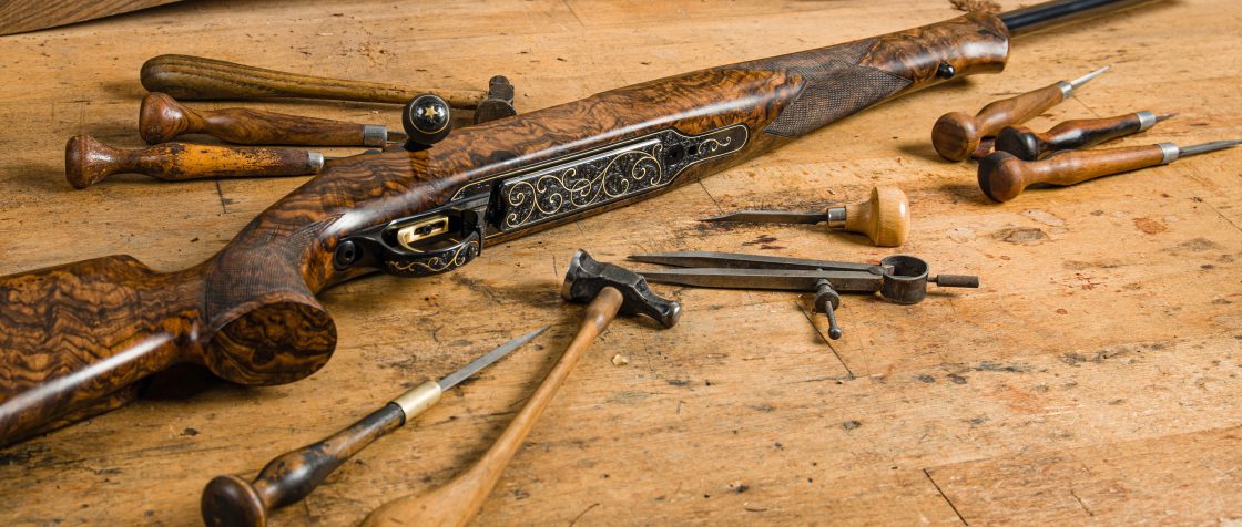 Antique rifle on a worktable surrounded by tools