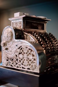 Side view of a vintage metal cash register with a floral engraved pattern