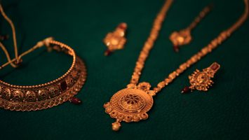 Antique gold necklaces and earrings against a dark green background