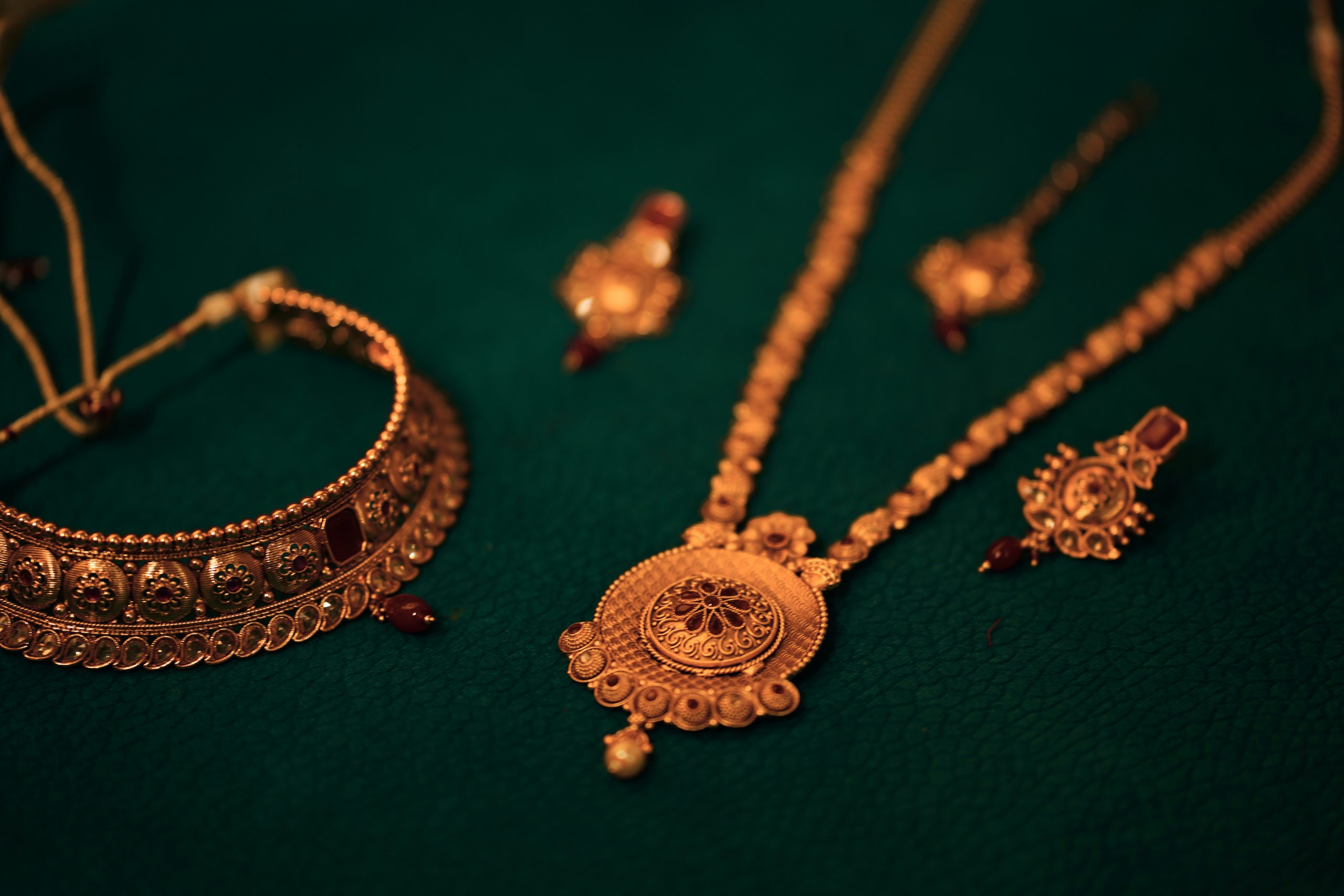 Antique gold necklaces and earrings against a dark green background