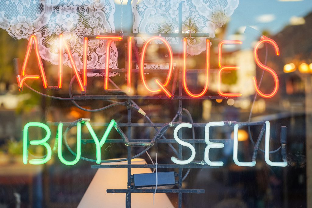 Neon sign reading "Antiques: Buy Sell"