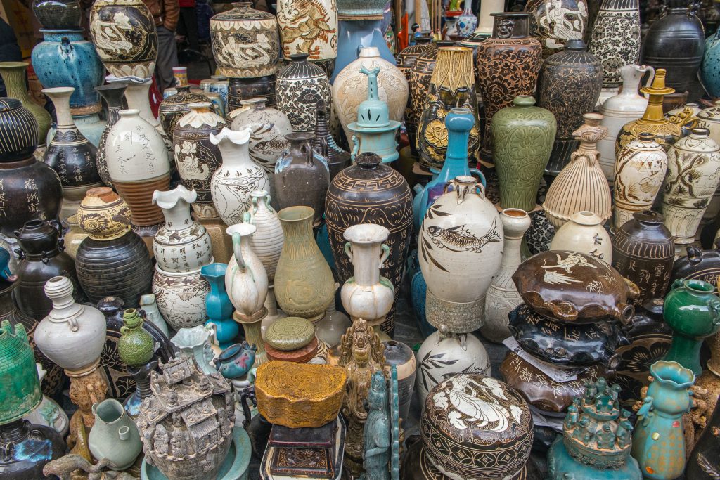 Different styles of antique vases stacked together at a flea market