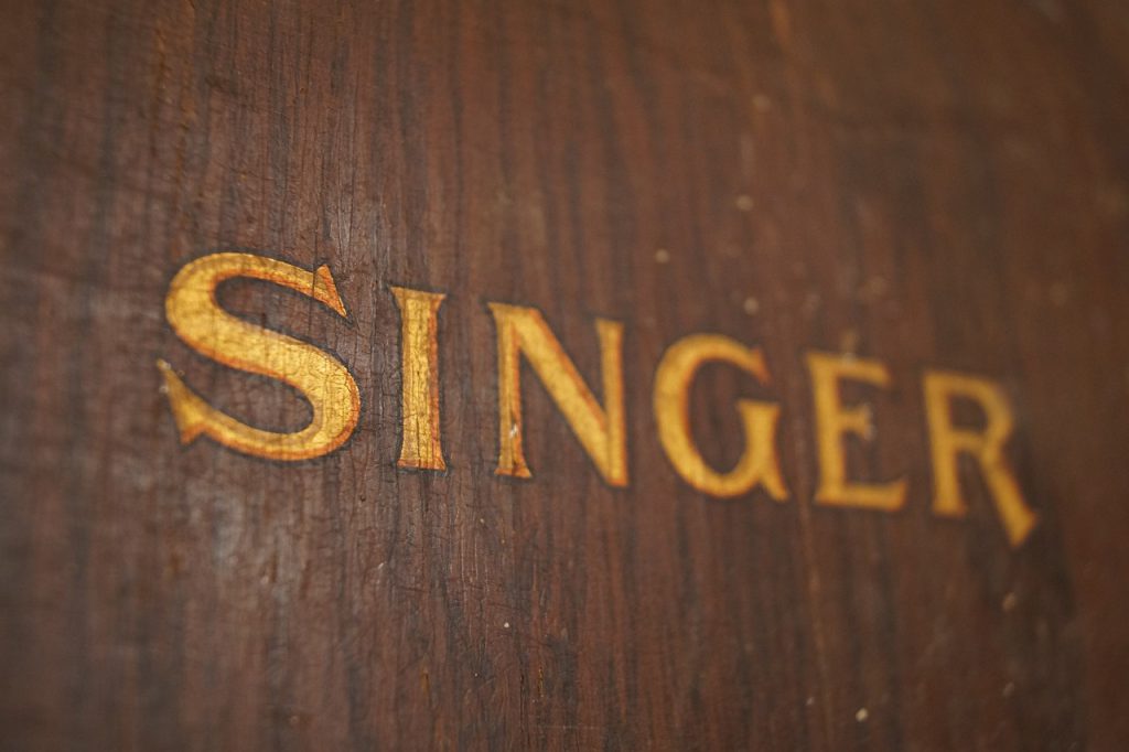 Closeup of gold singer sewing machine logo carved into wood.
